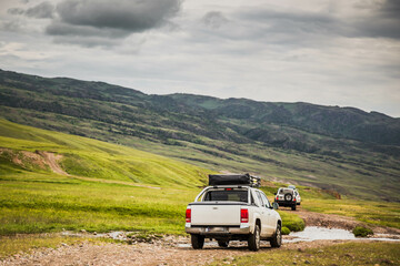 cars is moving along a dirt road. travel by car in the mountains. rough road in the steppe. jeeps make their way through the desert