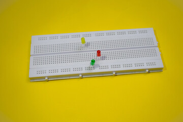 Electronic breadboard for college experiments with LED or light emitting diode isolated on a yellew...
