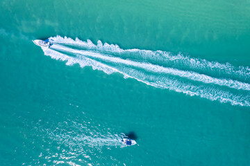 Drone view of sea with crystal clear blue water. Attractive men swimming on sea.