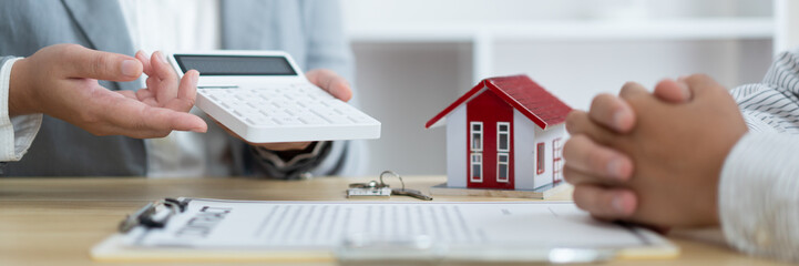 The selling agent informing his client about the expense by showing it on the calculator