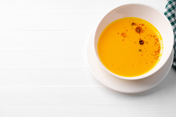 Pumpkin creamy soup served in bowl on white wooden background