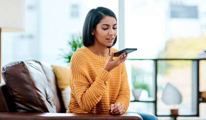 When were communicating, were connecting. Shot of a young woman using a smartphone on the sofa at home.