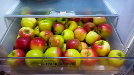 Ripe apples in a fruit box in the refrigerator.