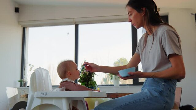 loving mother feeding baby son at home