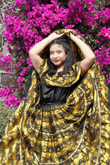 Young woman wears a traditional regional dress from the state of Chiapas, Mexico proud of the culture and tradition of her country with jacaranda flowers in the background
