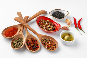 Colorful spices in the wooden spoons on white background.