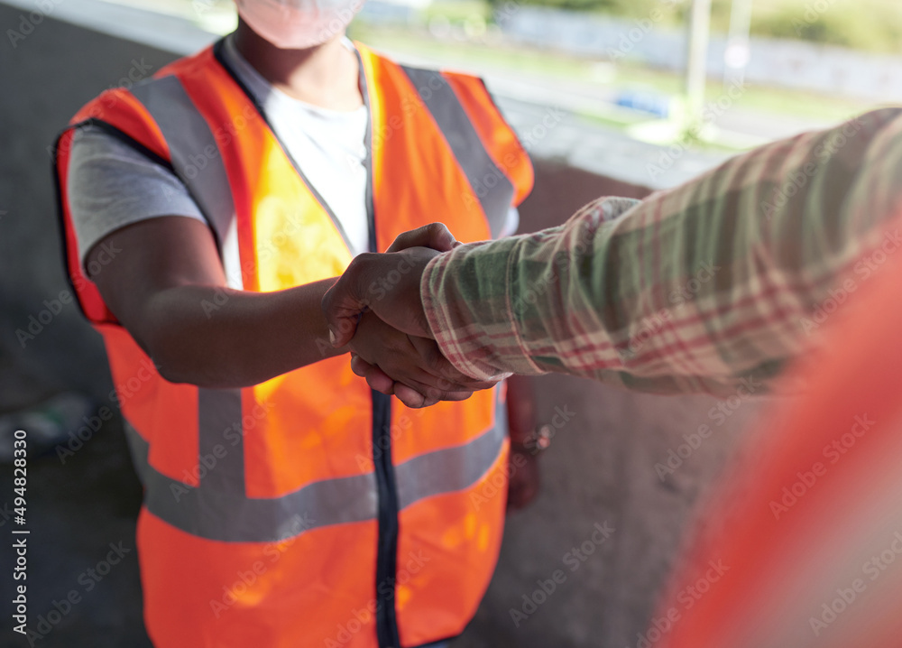 Poster lets work together to build even better. shot of two builders shaking hands at a construction site.
