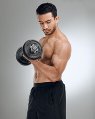 If you want to look good, you have to lift heavy. Shot of a man working out with weights while standing against a grey background.