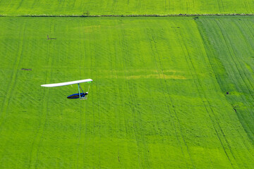 Hang glider flying a green field