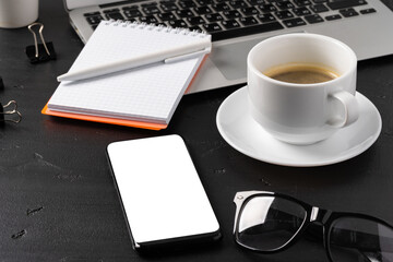 Notepad is on top of office desk table with laptop and supplies