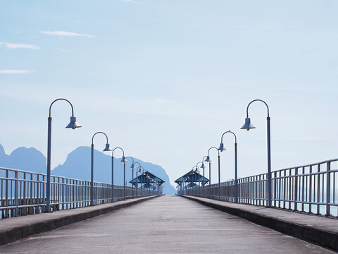 Concrete bridge with lighting poles on the sea over blue sky background at pier.