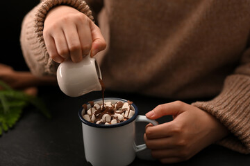 Fototapeta na wymiar Close-up, A woman pouring a chocolate syrup on a hot chocolate with marshmallow.