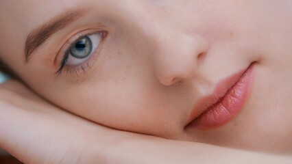 Detail of young woman laying on her hand open eye and look at camera