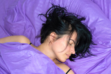 brunette woman sleeping in purple bed