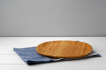 Wooden cutting board on cotton napkin on white wooden table