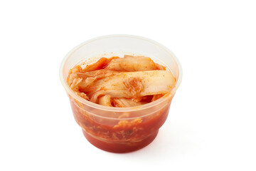 Marinated kimchi with vegetables such as lettuce, carrots in a small plastic cup isolated on a white background, Kimchi is a traditional dish in Korean cuisine. It is often eaten as a side dish.