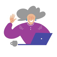 A happy smiling elderly woman waves her hand while sitting at the computer
