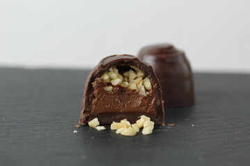 CHOCOLATE CASE CANDY WITH CHOCOLATE FILLING PRALINE GANACHE AND CRUSHED PEANUTS ON A GRAY BLACK...