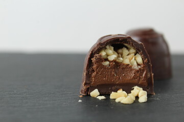 CHOCOLATE CASE CANDY WITH CHOCOLATE FILLING PRALINE GANACHE AND CRUSHED PEANUTS ON A GRAY BLACK BACKGROUND. Day of chocolate sweets without diet