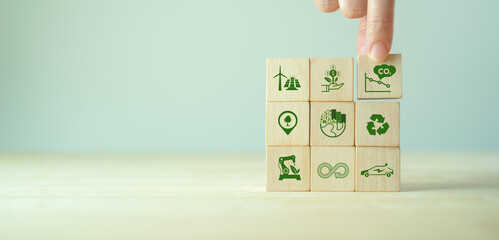Low carbon,carbon neutral concept. Net zero greenhouse gas emissions target. Climate neutral long term strategy. Hand put wooden cubes with decrease carbon emission icon and green icon. Green banner. - obrazy, fototapety, plakaty
