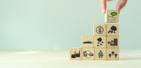 Low carbon emission and net zero concept. Climate changing problems solving goals. Stacking wooden cubes with decarbonization icon on pollution causes icons on grey background,copy space. LCA.