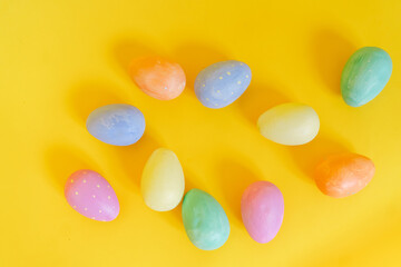 multi-colored Easter eggs lie on a yellow background, top view