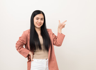 Beautiful asian women in pink fashion suit standing pose looking at camera pointing finger to blank space for advertise. Attractive Happy female portrait in white studio. Smiling woman age around 20