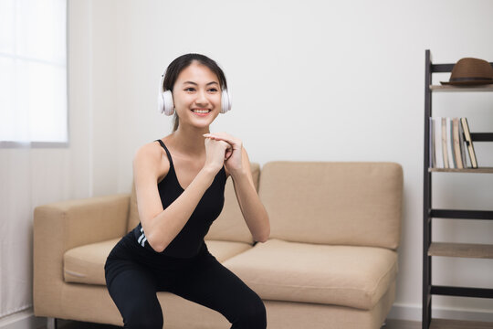 Young beautiful fitness asian woman doing squat sit up exercise workout at home. Attractive female warming up body training wearing sportswear. Side view Sporty girl stretching warm up cardio body.