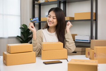 Fototapeta na wymiar Shopping online. Young asian woman holding credit card for shopping payment. Buy item online delivery at home. Small business entrepreneur with many parcel box on table