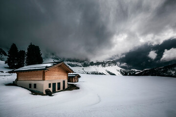 house in the mountains covered with snow under dark clouds
