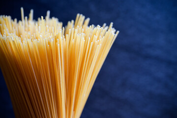 Yellow long spaghetti on a rustic background. Yellow italian pasta. Long spaghetti. Raw spaghetti bolognese. Raw spaghetti. Food background concept. Italian food and menu concept.