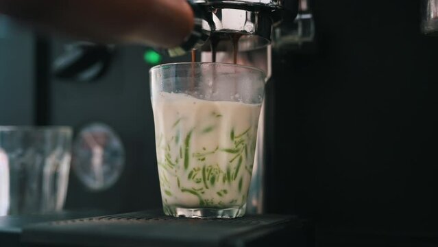 Pouring coffee stream from machine in cup with milk. Home making hot Espresso. Using filter holder. Flowing fresh ground coffee. Dirty coffee concept