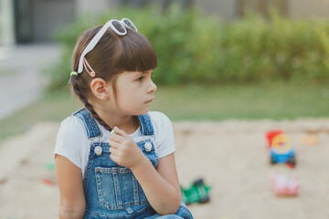 close-up portrait of a toddler girl 4 years old, pensive on the playground in summer.