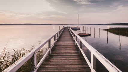 Fototapeta na wymiar Morgendliche Ruhe an einem See mit langem Bootssteg horizontal