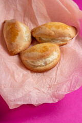 Sochniki, sochni, with cottage cheese. Cookies stuffed with cottage chees on a pink background. Copy space. 