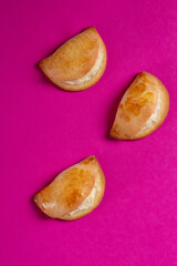 Sochniki, sochni, with cottage cheese. Cookies stuffed with cottage chees on a pink background. Copy space. 