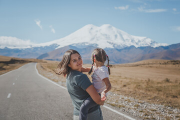 mother and daughter on a trip to the Caucasus, on a beautiful road jyly su in autumn against the backdrop of Mount Elbrus in Russia
