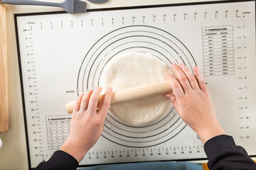 Rolling out dough on a silicone baking mat with round markings of different diameters, top view