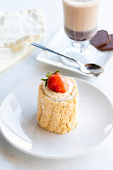 Strawberry log cake on a white background. With hot chocolate on the side. close up