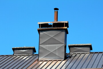 Elongated narrow concrete chimney covered with dark grey metal sheet protection and stained from...