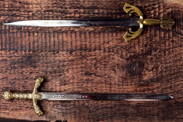 Two antique knight's sword on the background of gray wood texture. Religion and culture