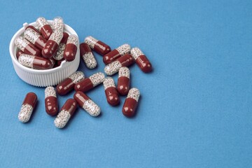 Colored capsules with medical drugs on a blue background. Copy space, flat lay