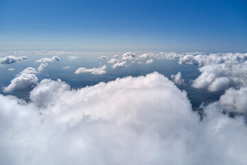 Aerial view from airplane window at high altitude of earth covered with white puffy cumulus clouds