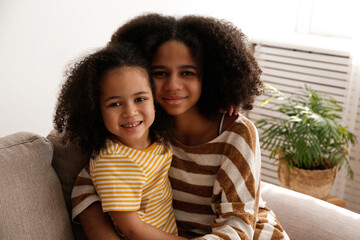 Younger and older sister spending time together at home. Two black girls of different age messing...