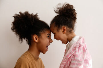 Younger and older sister in a state of emotional stress displeased with each other. Two black girls of different age arguing. Black female siblings having a fight. Background, copy space, close up. - obrazy, fototapety, plakaty
