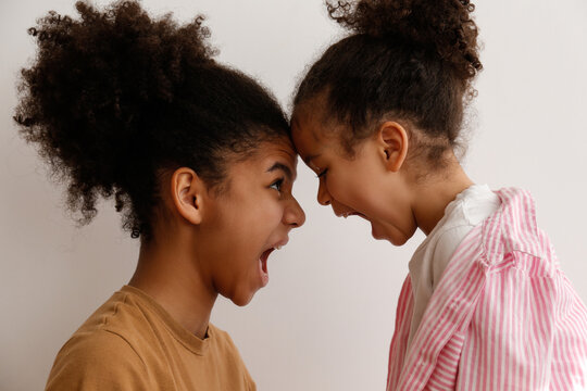 Younger and older sister in a state of emotional stress displeased with each other. Two black girls of different age arguing. Black female siblings having a fight. Background, copy space, close up.
