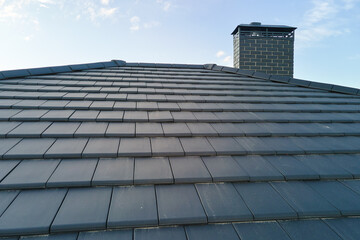 Closeup of house roof top covered with ceramic shingles. Tiled covering of building
