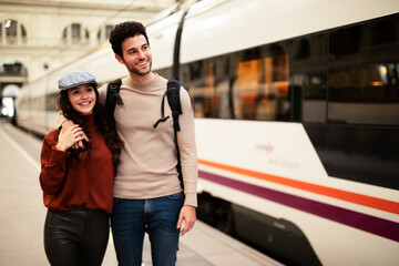 Beautiful couple at railway station waiting for the train. Young woman and man waiting to board a train