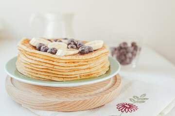 Pancakes on pile are covered with honey, blueberries and banana slices on plate. Healthy tasty breakfast