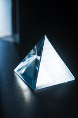 A glowing prism on a table on a dark background. A prism in the shape of a pyramid. Prism for design